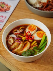 Close-up of a flavorful Asian ramen bowl topped with boiled eggs, vegetables, and chili.
