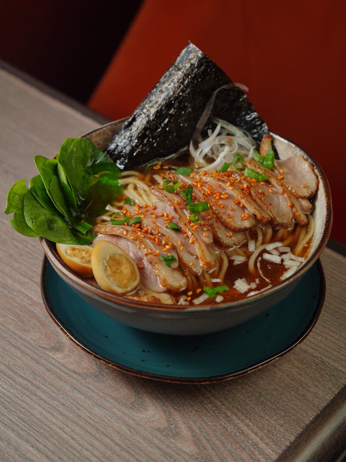 A flavorful bowl of Japanese ramen with sliced pork, egg, and seaweed, ideal for food enthusiasts.