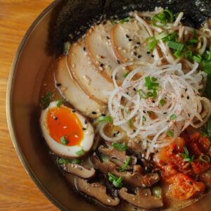 A flavorful ramen bowl with egg, mushrooms, and seaweed in a cozy setting.